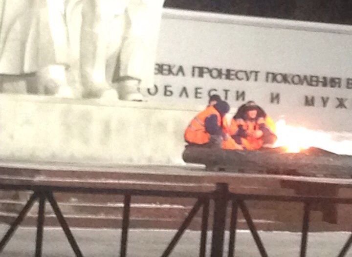 Фото: рабочие греются у Вечного огня на площади Победы